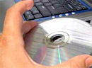 Tvorba software na míru Ruka drží CD a vkládá do DVD mechaniky notebooku